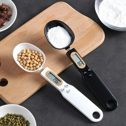 one white and one black digital weighing spoon with lentils and sugar